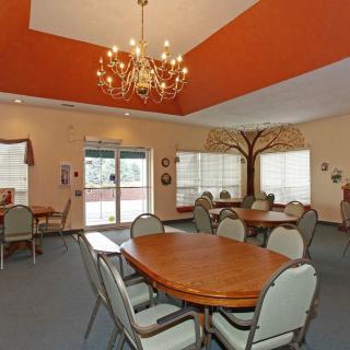 A well-lit meeting room with a chandelier, tables, and chairs.