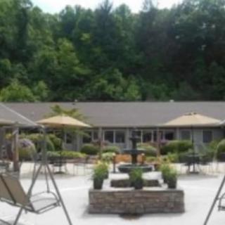 A scenic outdoor patio with seating areas, umbrellas, and lush greenery in the background.