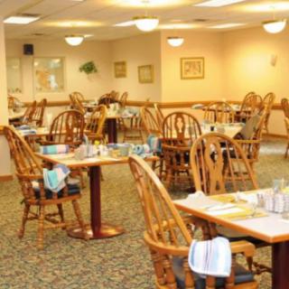 An indoor dining room with wooden tables and chairs arranged for service.