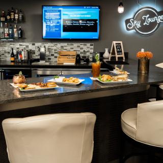 Cozy bar interior with seating, food, and a drinks menu on display.