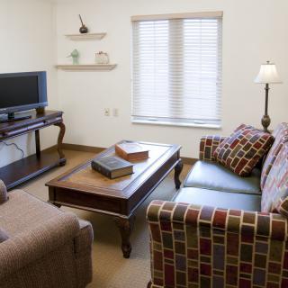 A cozy living room with a patterned sofa, coffee table, and television.