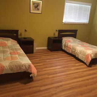 A bedroom with two twin beds, wooden flooring, and a window.