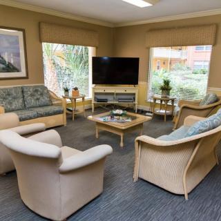 A cozy living room with comfortable seating, a large television, and natural light from the windows.
