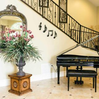A luxurious living area featuring a grand piano, a decorative plant, and intricate staircase railing.