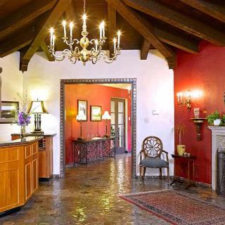 A traditional living room featuring a chandelier, wooden beams, and a cozy fireplace.