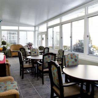 A bright indoor dining area with large windows, tables, and chairs.
