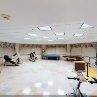 A spacious fitness room equipped with stationary bikes, treadmills, and therapy beds.