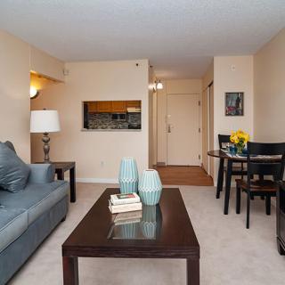 A cozy living room with a sofa, coffee table, and dining area in a modern apartment.