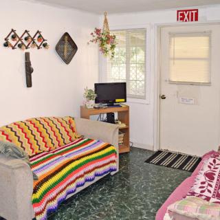 A cozy living room with colorful blankets and wall decorations.