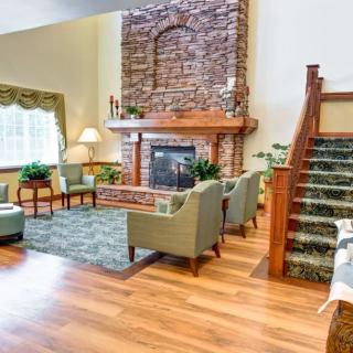 A cozy living room with a stone fireplace, comfortable seating, and hardwood flooring.