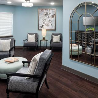 A cozy living room with modern decor featuring comfortable seating and a large decorative mirror.
