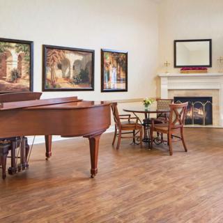 A stylish living room with a grand piano, elegant furniture, and artwork on the walls.