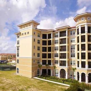 A large residential apartment complex with multiple stories and balconies under a partly cloudy sky.