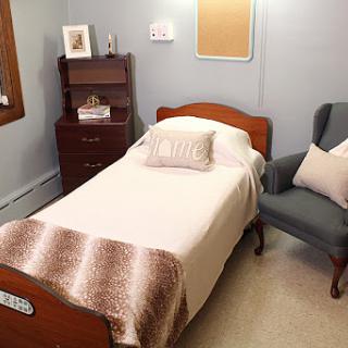 A cozy bedroom featuring a single bed, a comfortable armchair, and tasteful decor.