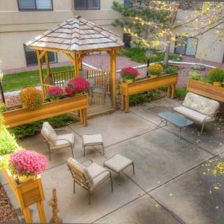 A cozy outdoor patio with a gazebo, seating area, and vibrant flowers.