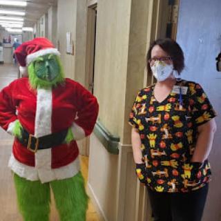 A festive moment captured in a healthcare setting with the Grinch and a nurse.