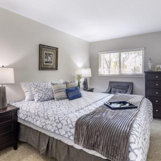 A cozy bedroom featuring a large bed with patterned bedding, complemented by bedside lamps and a dresser.