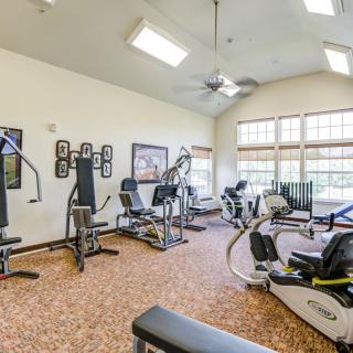 A well-equipped gym with various exercise machines and bright natural lighting.