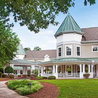 A charming Victorian-style house with a well-manicured garden and lush greenery.