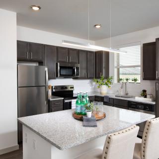 A modern kitchen with stainless steel appliances and a granite island countertop.