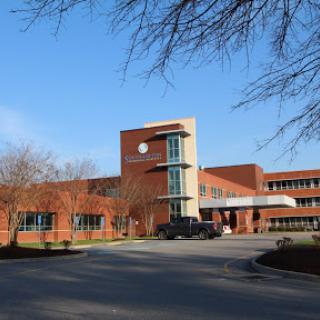 A modern healthcare facility set against a clear blue sky.