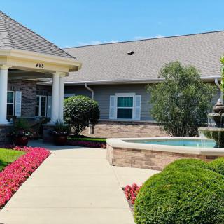 A beautifully landscaped house entrance with a fountain and vibrant flowers.