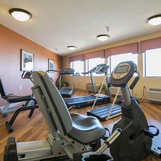 A well-lit gym with various fitness equipment including treadmills and a stationary bike.