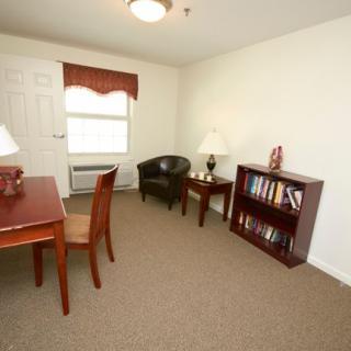 A simple office space with a desk, chair, bookshelf, and lamps.