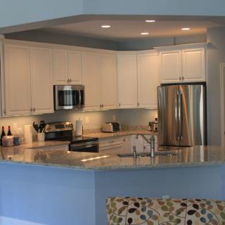 Modern kitchen with white cabinets and stainless steel appliances.
