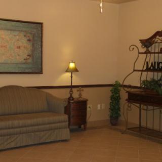 A cozy lobby area featuring a comfortable sofa, a decorative lamp, and wall art.