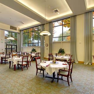 An elegant dining room with neatly arranged tables and chairs, featuring large windows and a spacious atmosphere.