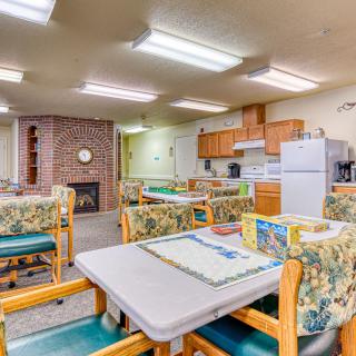 A cozy dining and kitchen area with tables, chairs, and kitchen appliances.