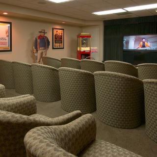 A cozy home theater setup with comfortable seating, a movie playing on the screen, vintage posters on the walls, and a popcorn machine.