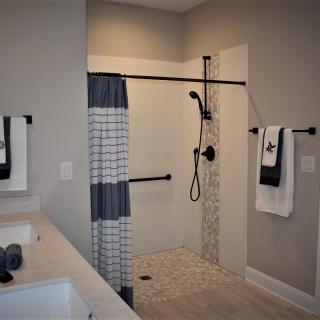 A modern bathroom with a walk-in shower, featuring neutral tones and minimalist decor.