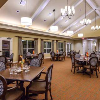 A spacious dining room with elegant furniture and chandeliers.