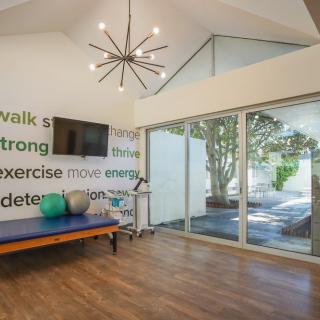 A modern exercise room featuring minimalist decor, large windows for natural light, and inspirational quotes on the wall.