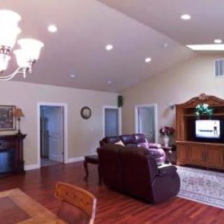 A spacious living room with a sofa, television, and dining area featuring hardwood floors and elegant lighting.