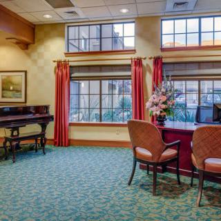 A well-decorated lobby area with chairs and a desk near large windows.