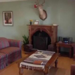 A cozy living room with a striped sofa, wooden coffee table, and a fireplace adorned with a deer head mount.