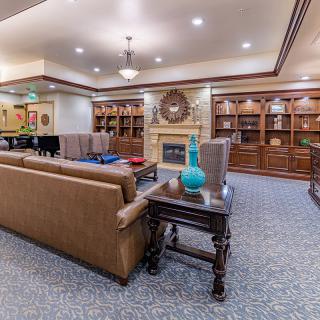 A spacious and elegantly furnished living room with sofas, a fireplace, and bookshelves.