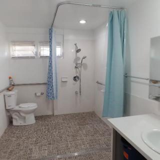 An accessible bathroom with a shower, toilet, sink, and grab bars.