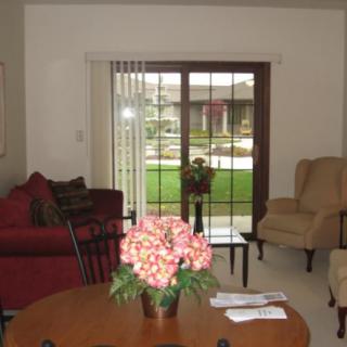 A cozy living room with comfortable seating, a table with flowers, and glass doors leading outside.