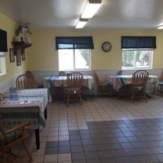 A cozy dining area with wooden tables and chairs, illuminated by natural light.