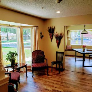 A cozy living room with a wooden floor, large windows, and comfortable seating.