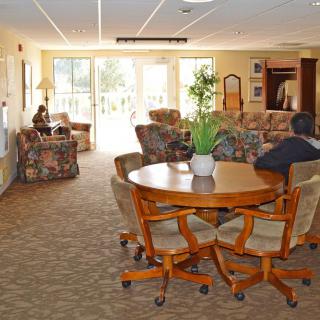 A cozy living room with a round table and chairs, surrounded by sofas and decorated with plants.