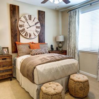 A cozy bedroom with warm tones and a large decorative clock above the bed.