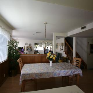 A cozy dining area with a table, chairs, and a flower arrangement under soft lighting.