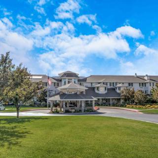 A large residential building with a well-manicured lawn and a bright blue sky overhead.