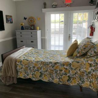 A cozy bedroom with floral bedding and a view of the outdoors through glass doors.