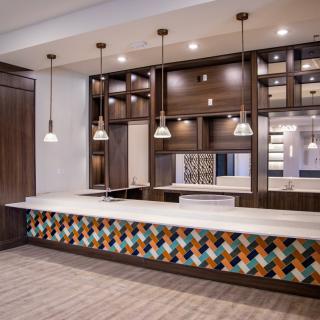A modern kitchen interior featuring pendant lights, wooden cabinetry, and a vibrant patterned backsplash.